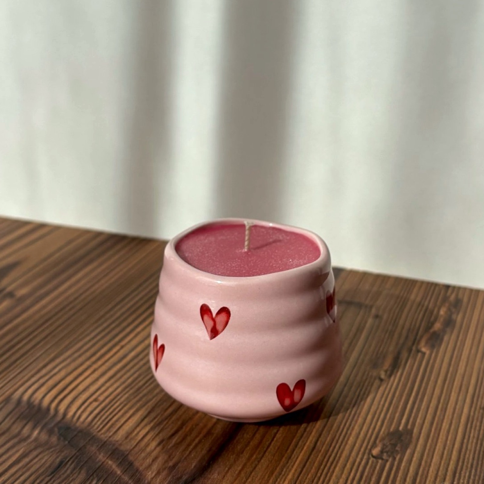 DUFTKERZE IN EINER ROSAFARBENEN GERILLTEN TASSE MIT ROTEN HERZEN