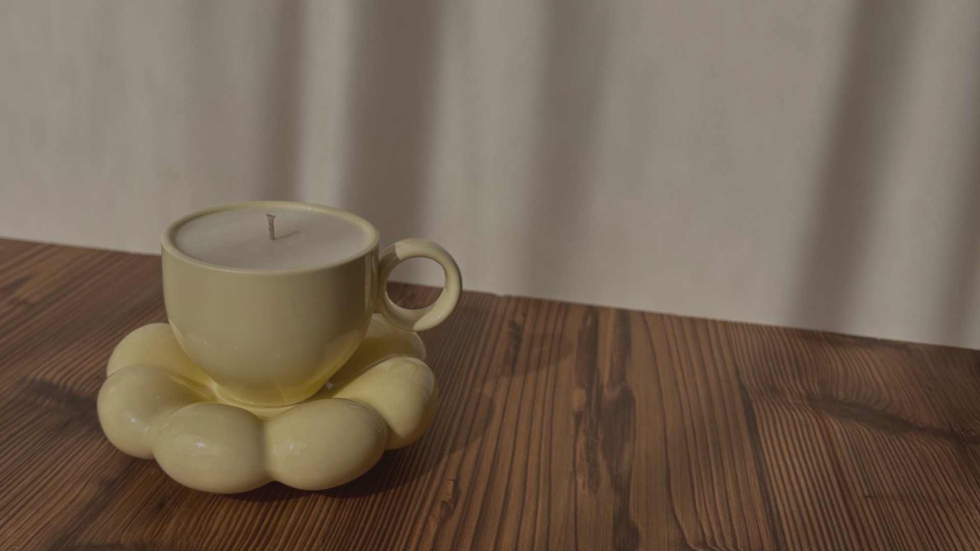 DUFTKERZE IN EINER TASSE AUF EINEM HOLZTISCH VOR EINEM VORHANG